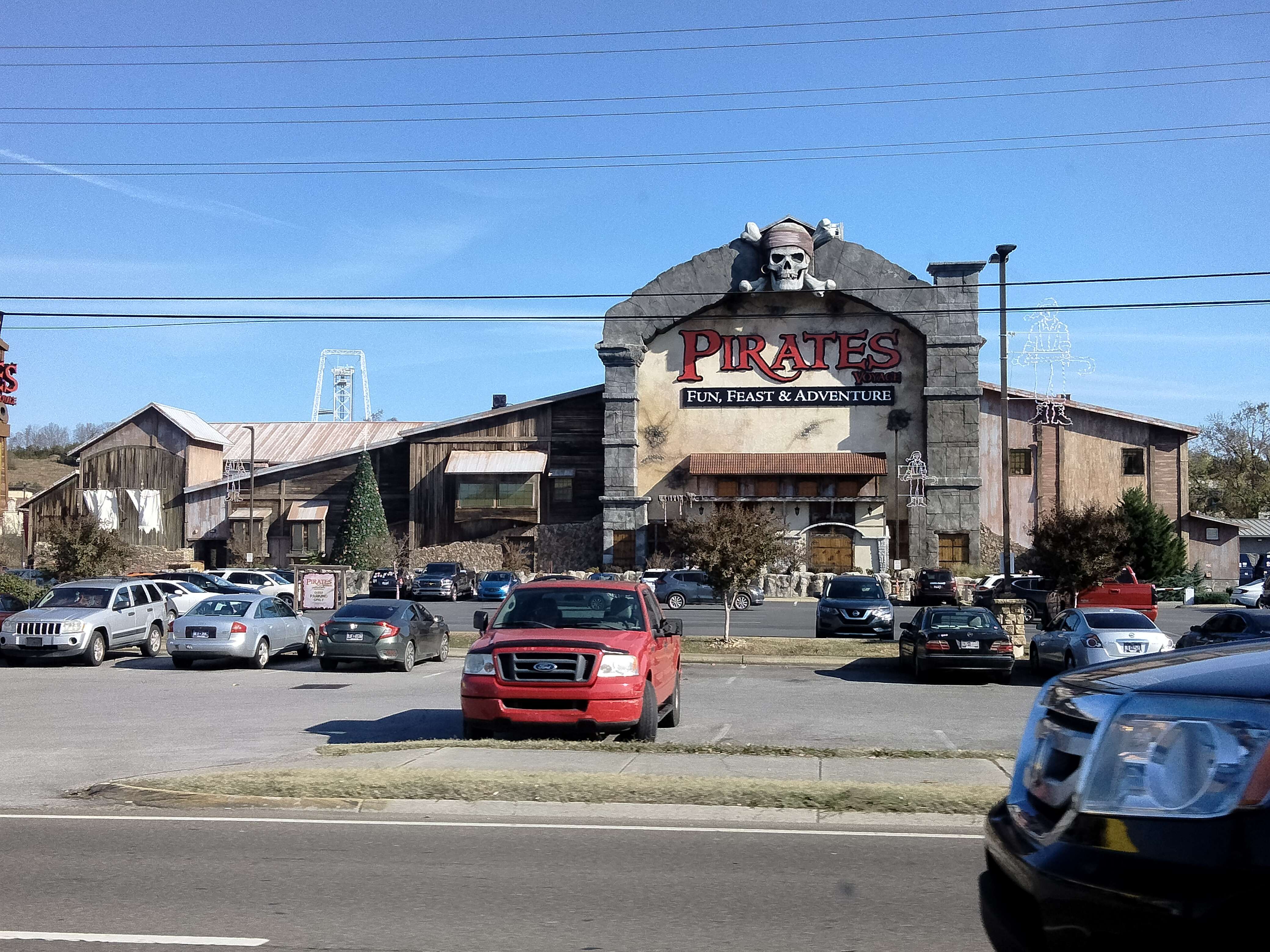 A picture of a roadside restaurant that is pirate-themed. It has a giant skull and crossbones over its entrance and is extravagantly themed to look like a big stone building with wooden rooms.